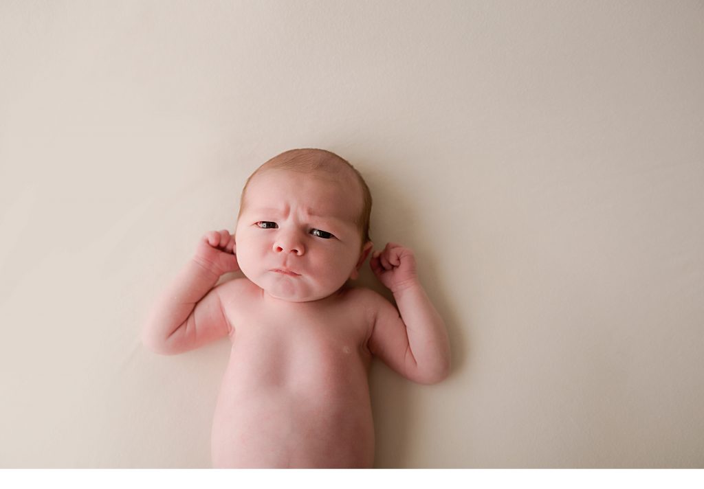 baby boy looking straight into the camera with an angry face in south jersey newborn session