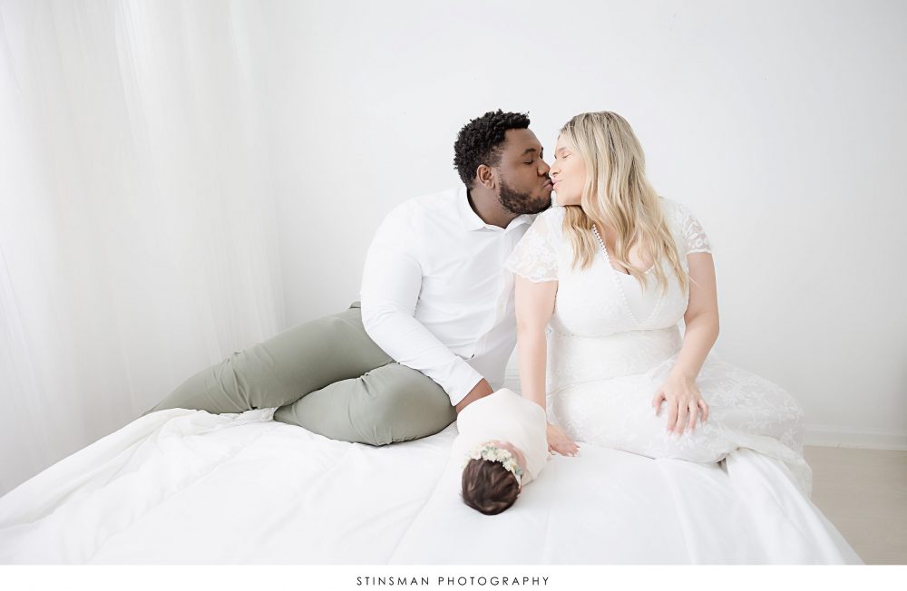 mom and dad kissing for newborn photo shoot