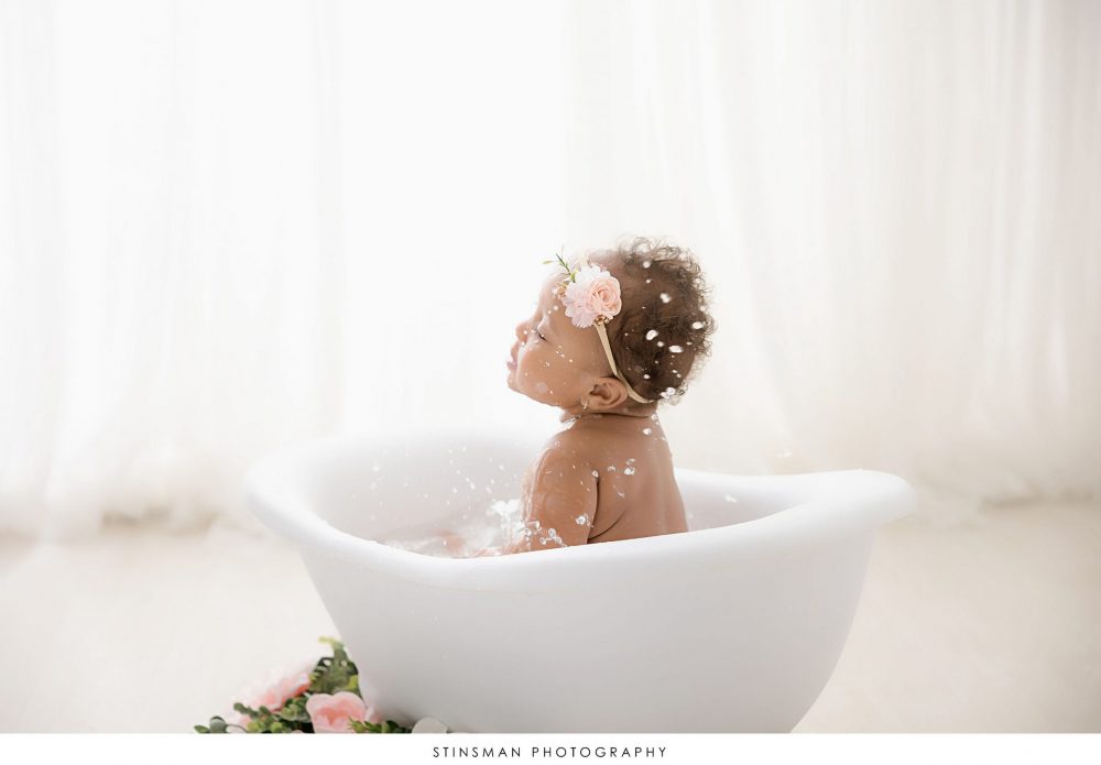 Baby girl playing in the tub at her one year old milestone photoshoot