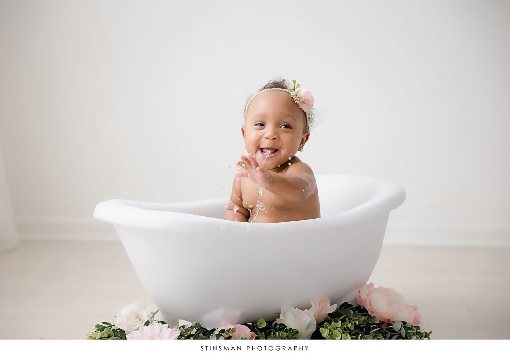 Baby girl happily splashing at her one year old milestone photoshoot