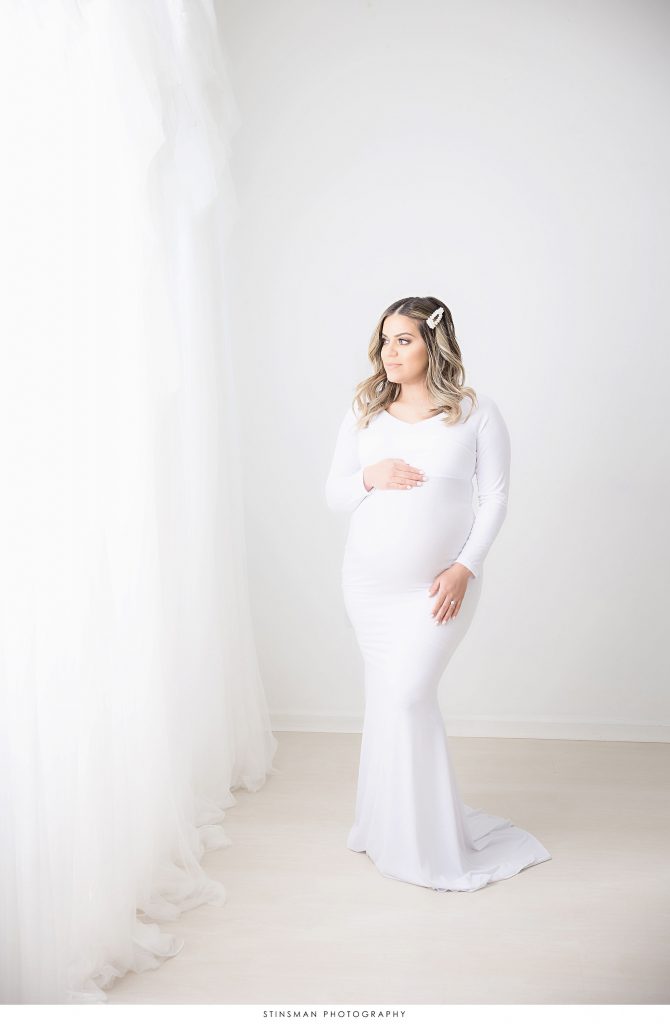 Pregnant mother in a white gown at her maternity photoshoot