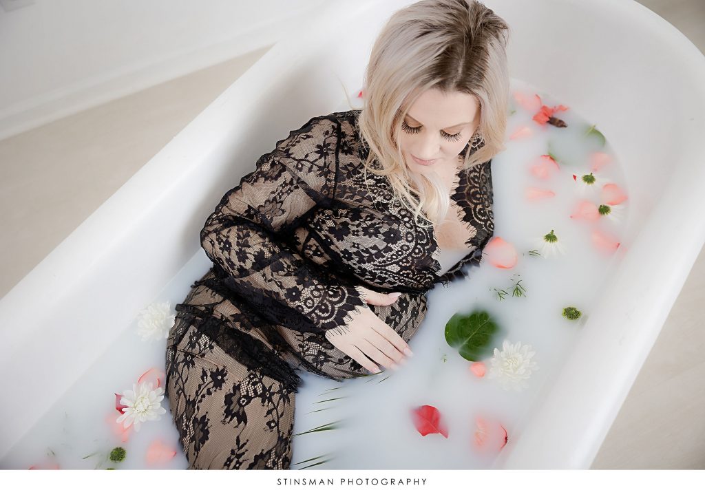 Pregnant mother in milk bath wearing black lace during her maternity photoshoot.