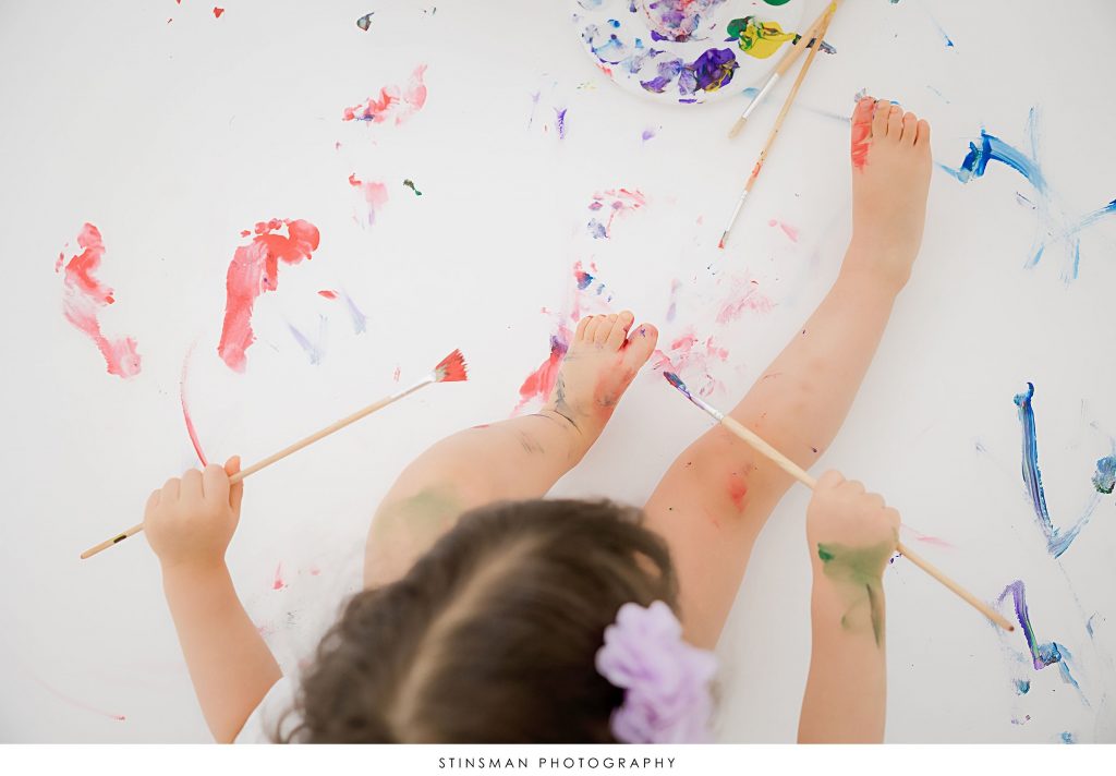 Little girl painting at her second birthday milestone photoshoot