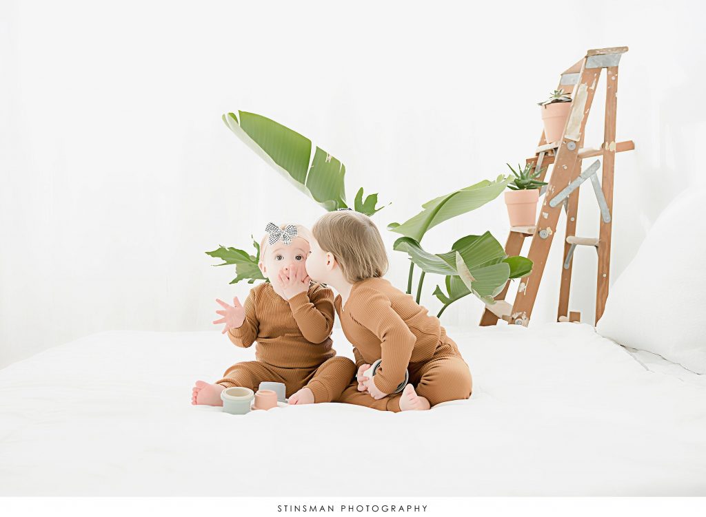 Sisters giving kisses at first birthday milestone photoshoot