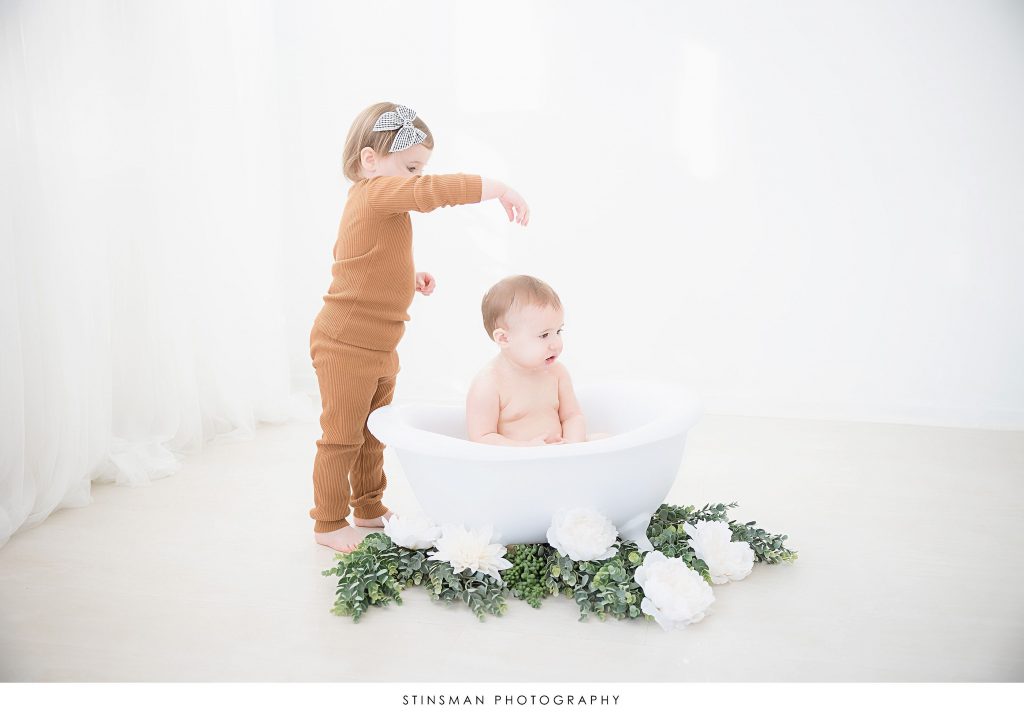 Big sister sprinkling baby sister at her first birthday milestone photoshoot