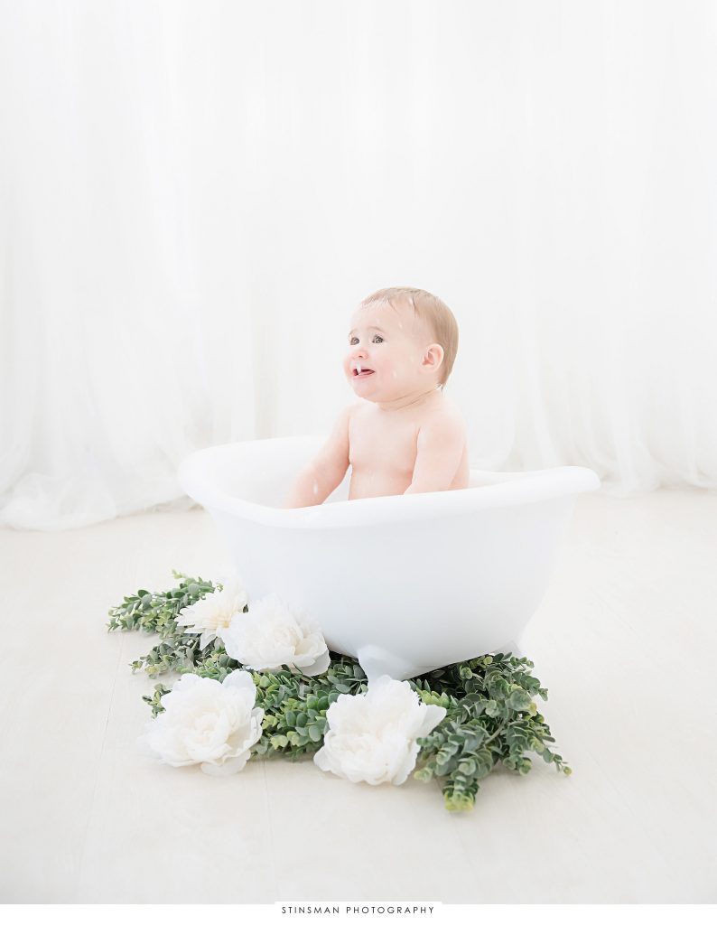 Baby girl happily splashing at her one year old milestone photoshoot