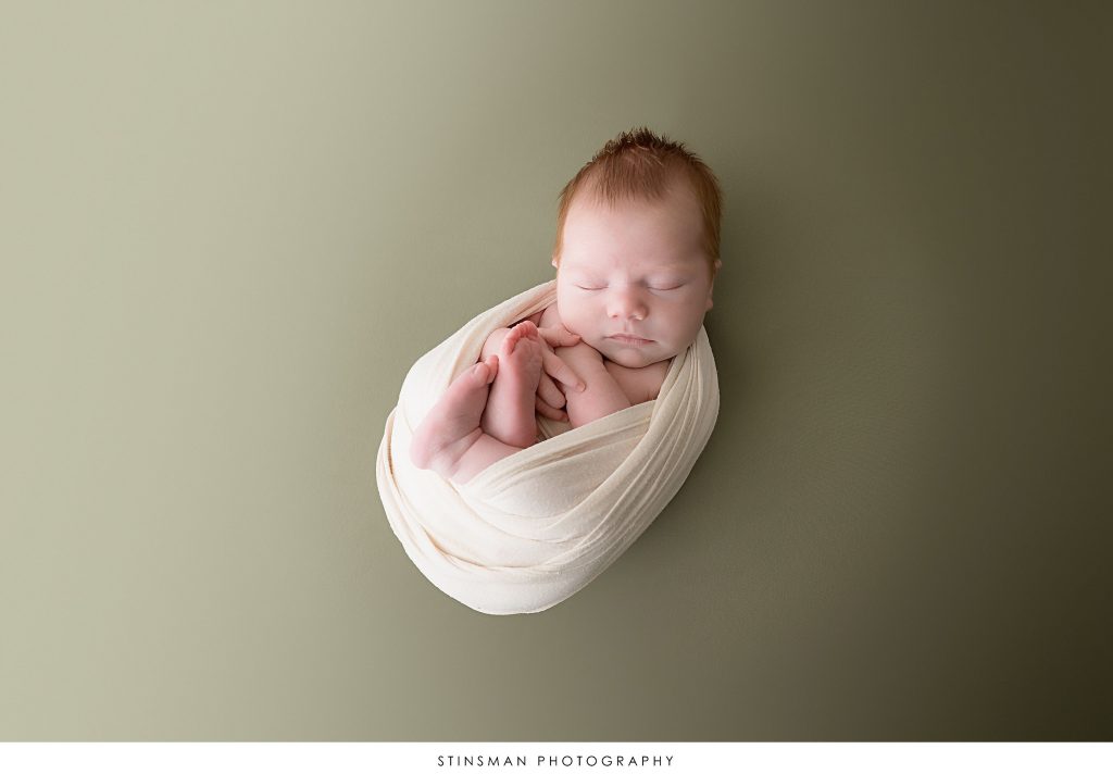 Newborn baby boy posed at his newborn photoshoot.