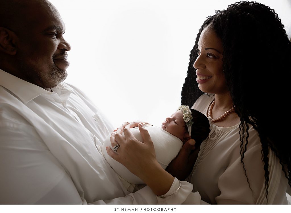 Mom and dad snuggling their baby girl at their newborn photoshoot