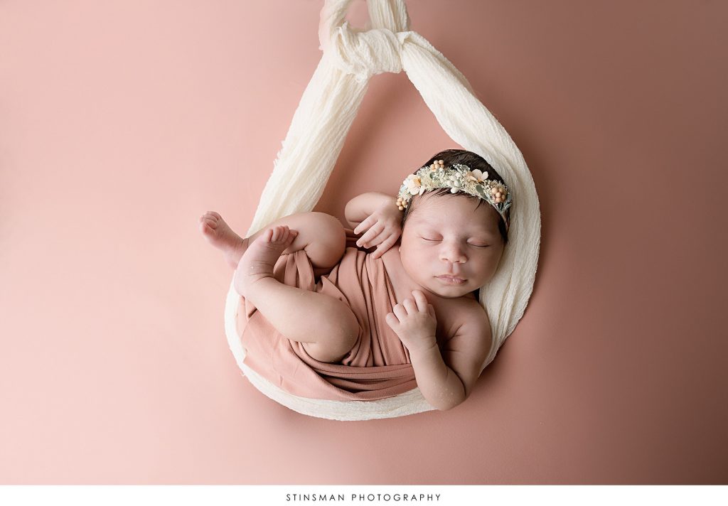 Newborn baby girl asleep in mauve wrap at her newborn photoshoot