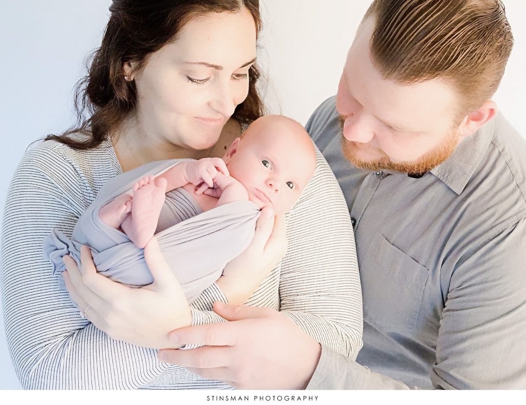 Mom and dad snuggling their newborn son at their newborn photoshoot