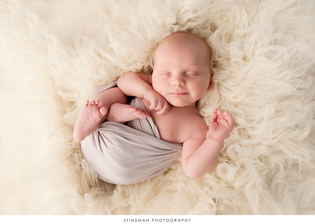 Newborn baby boy asleep and posed at his newborn photoshoot