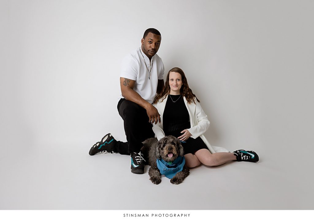 Pregnant mom and dad posing with their dog at their maternity photoshoot