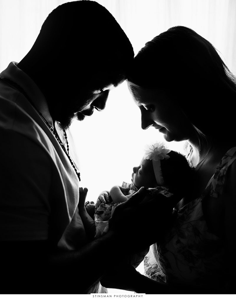 Mom and dad snuggling baby girl at their newborn photoshoot