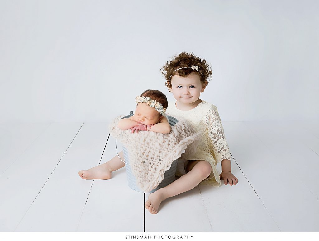 Newborn baby girl and her sister posed at her newborn photoshoot