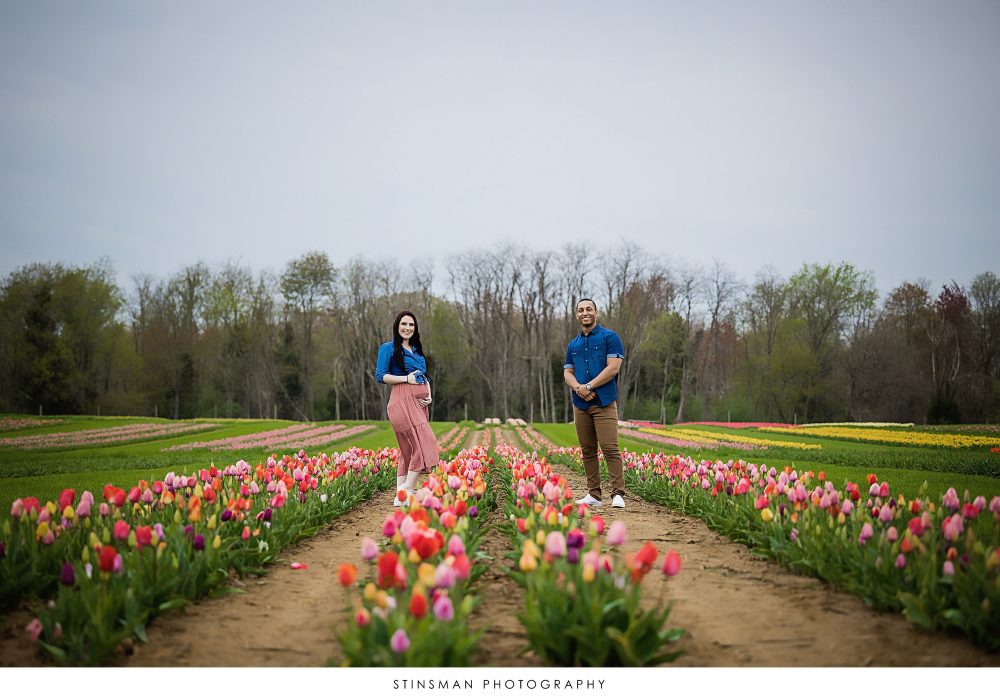Pregnant mom and dad posing at a tulip field for their maternity photoshoot