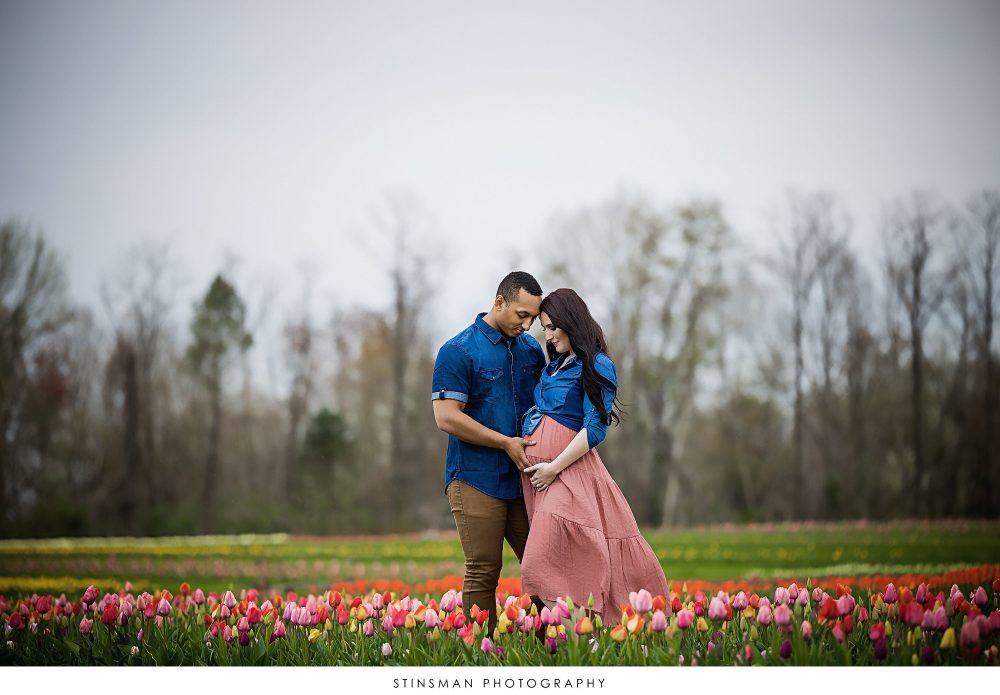 Pregnant mom and dad posing at a tulip field at their maternity photoshoot