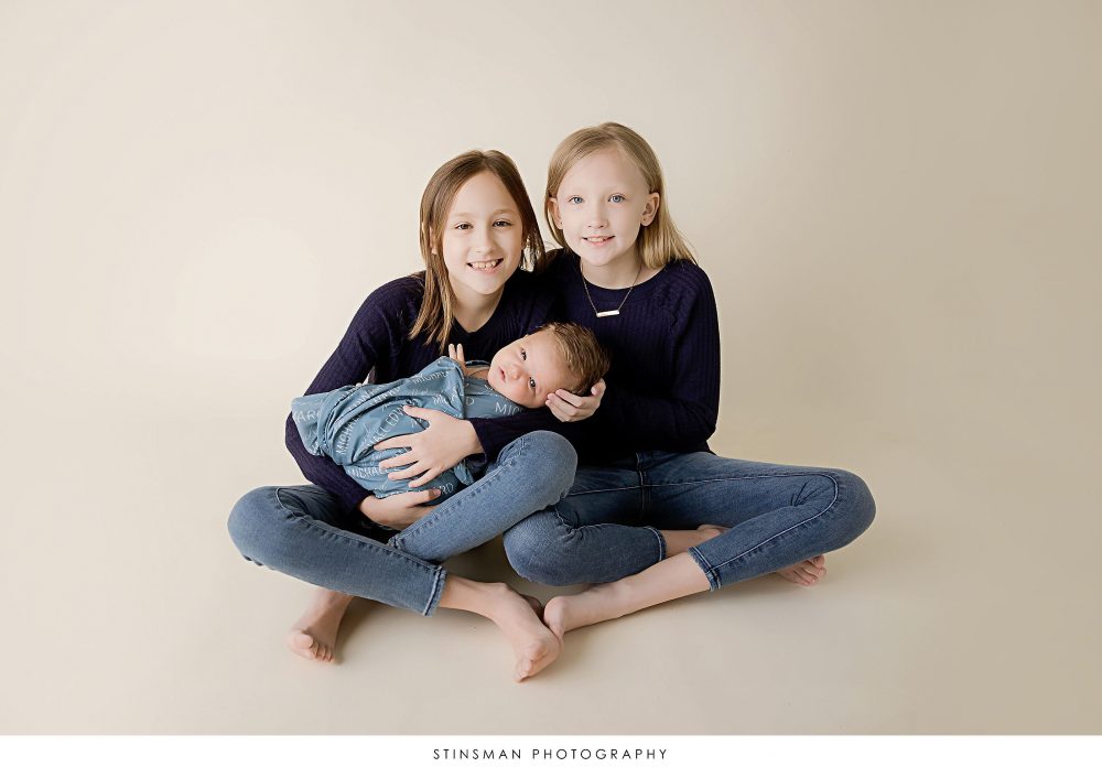 Newborn baby boy and his sisters posed at his newborn photoshoot