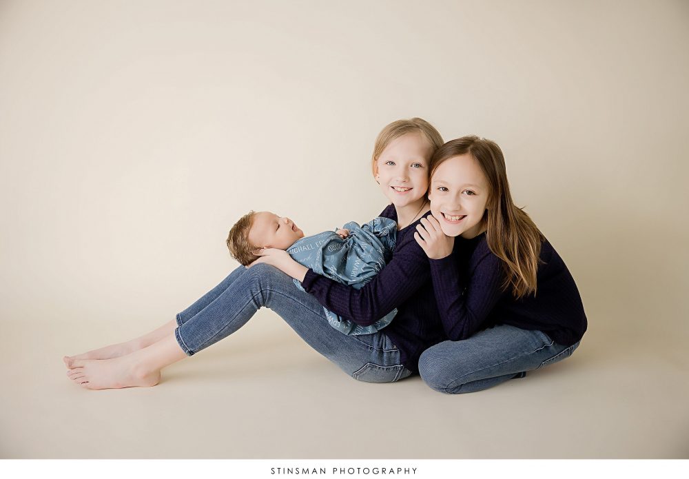 Newborn baby boy with his sisters posed at his newborn photoshoot