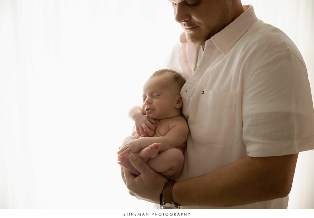 Dad with his newborn baby girl posing at their newborn photoshoot