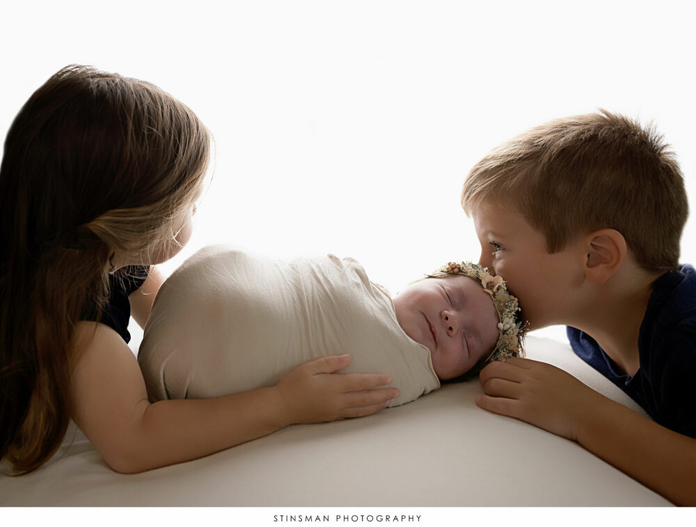 Newborn baby girl posed with her siblings at her newborn photoshoot