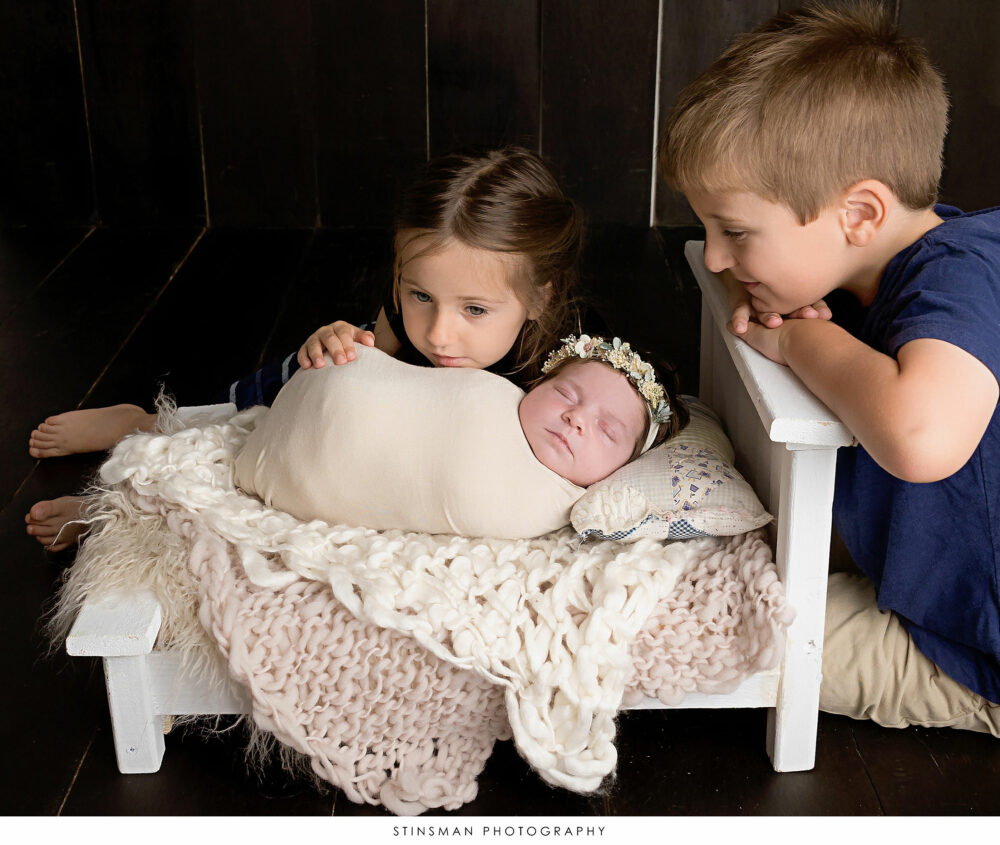 Newborn baby girl posed with her brother and sister at her newborn photoshoot