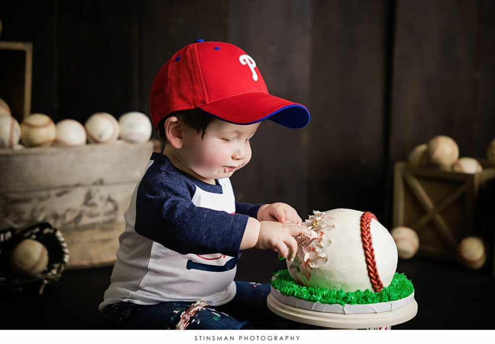 One year old boy digging into his cake at his milestone photoshoot