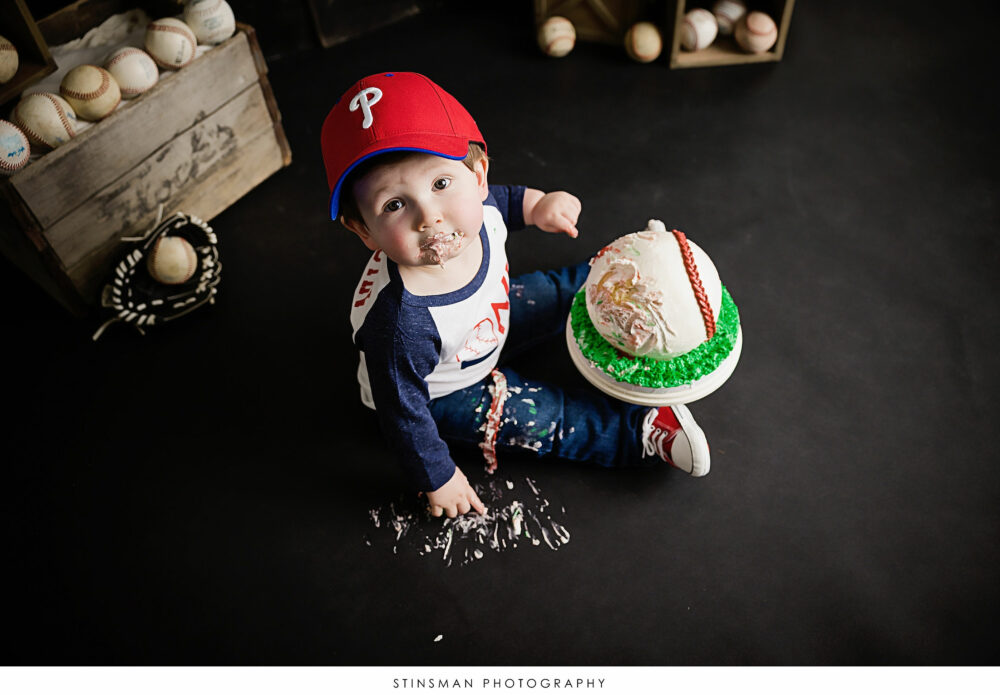 One year old boy posing with his cake at his milestone photoshoot