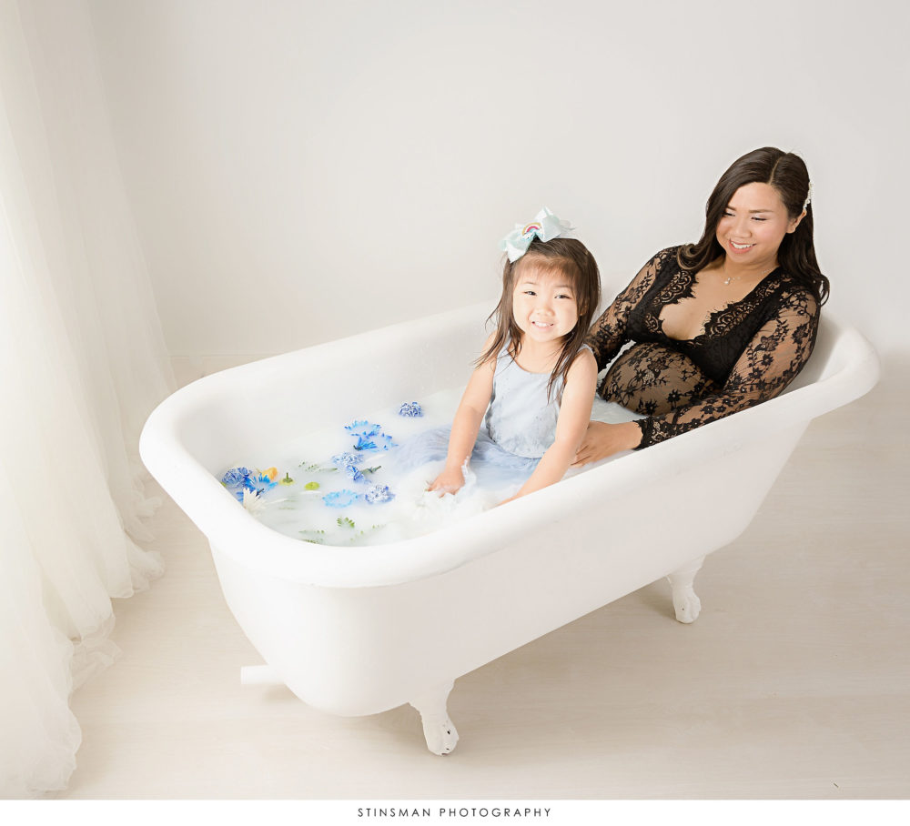 Pregnant mom to be in a milk bath with her daughter at her milk bath maternity photoshoot
