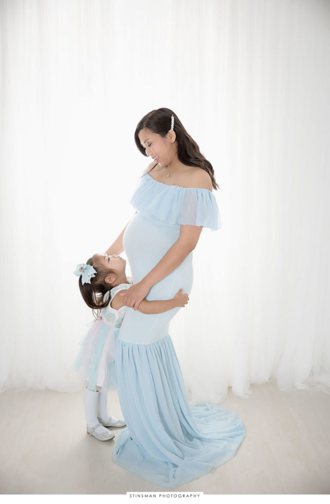 Pregnant mom posing with her daughter at her maternity photoshoot