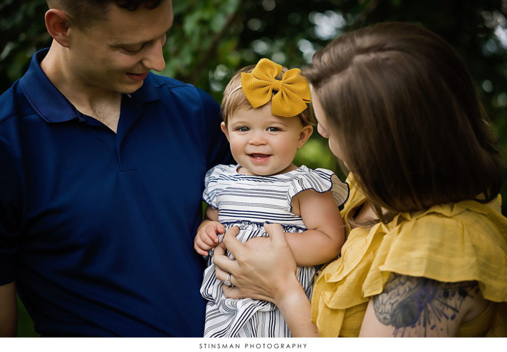 Baby girl smiling at mom and dad at milestone photoshoot