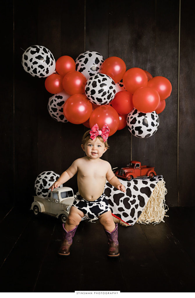 One year old girl posing at her cowgirl themed milestone photoshoot