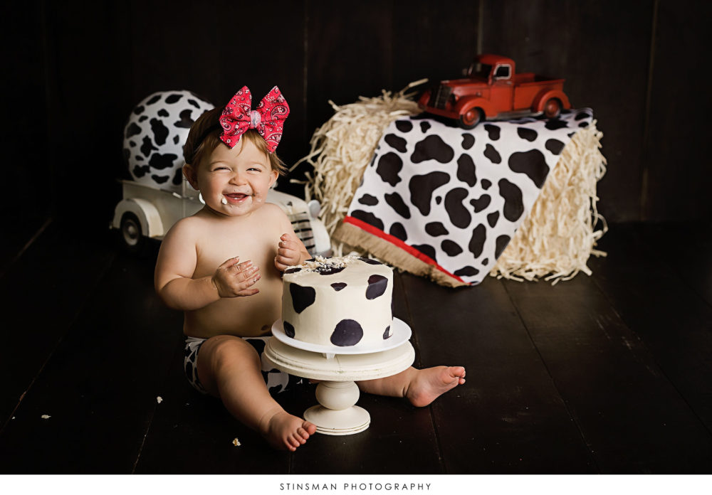 One year old girl eating her cake at her milestone photoshoot