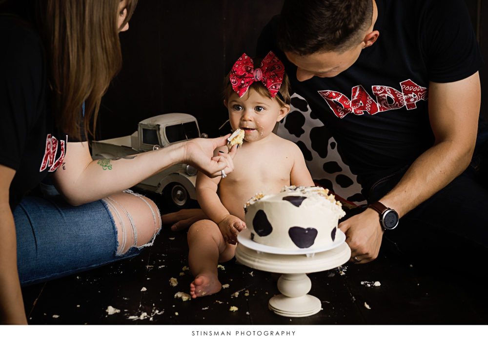 Mom and dad helping their one year old at her milestone photoshoot
