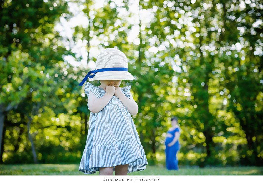 Little girl in a cute hat posing with her mom at her maternity photoshoot