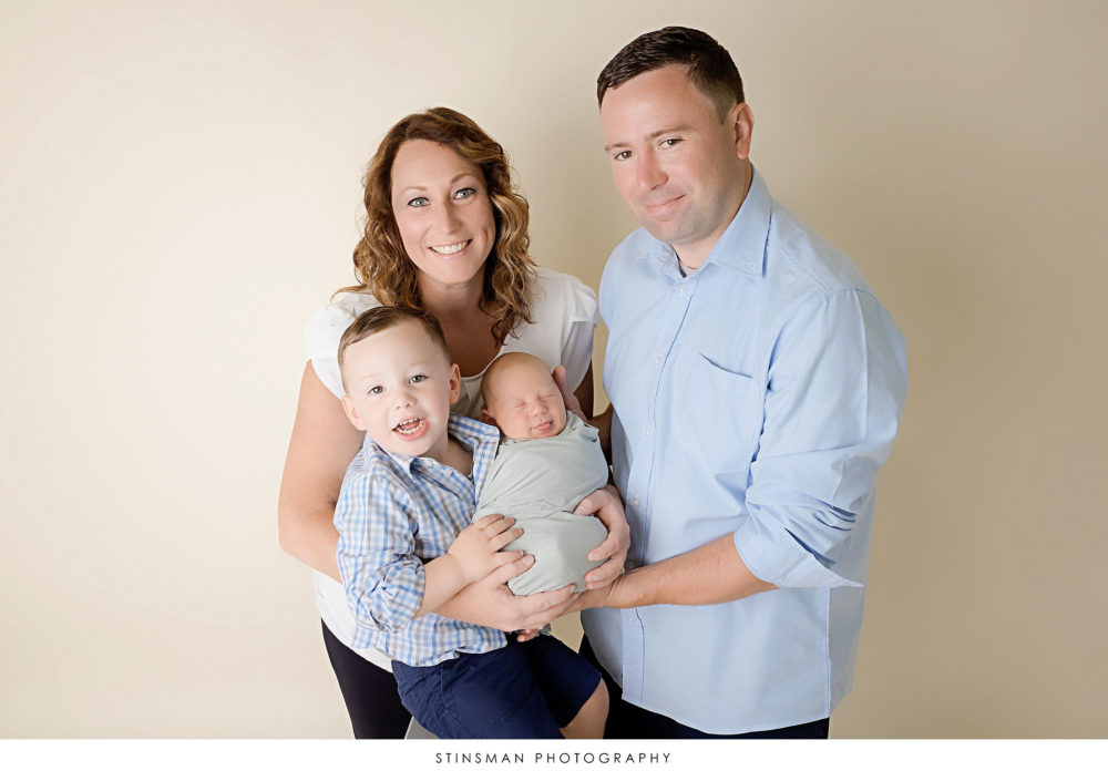 Family all posing with newborn baby boy at their newborn photoshoot