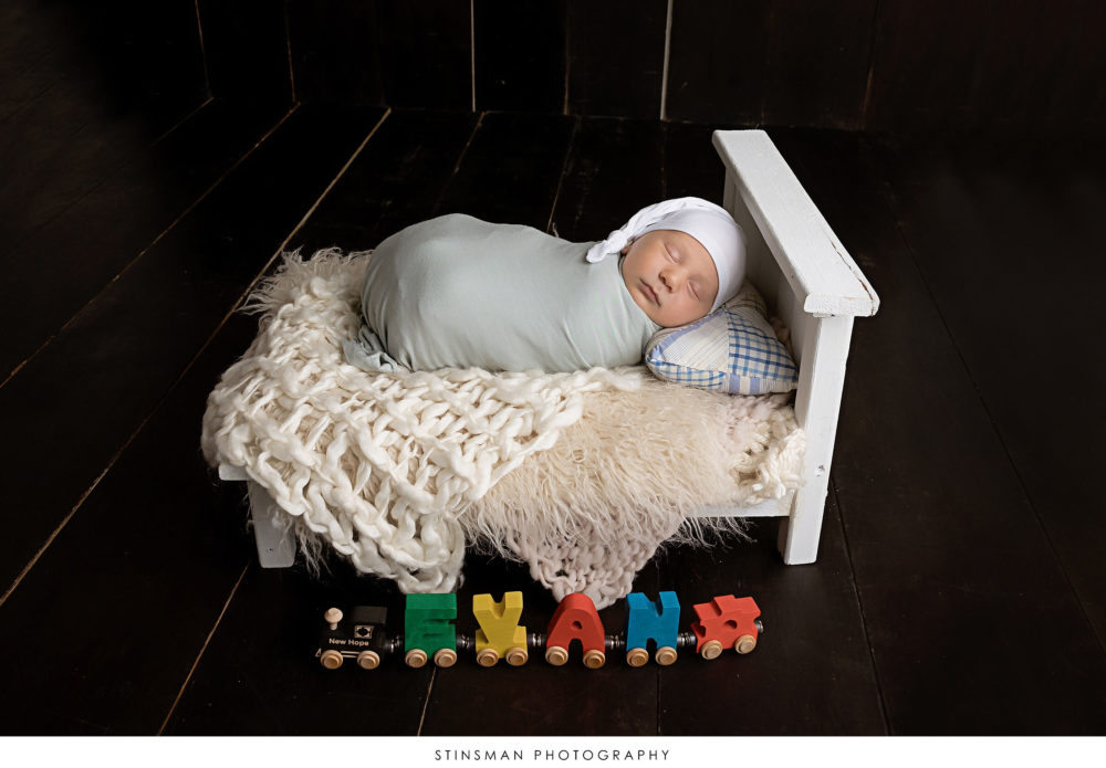 Newborn baby boy posed at his newborn photoshoot.