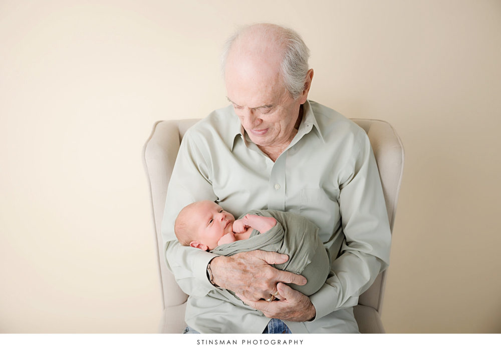 Newborn baby boy posing with his grandpa at his newborn photoshoot