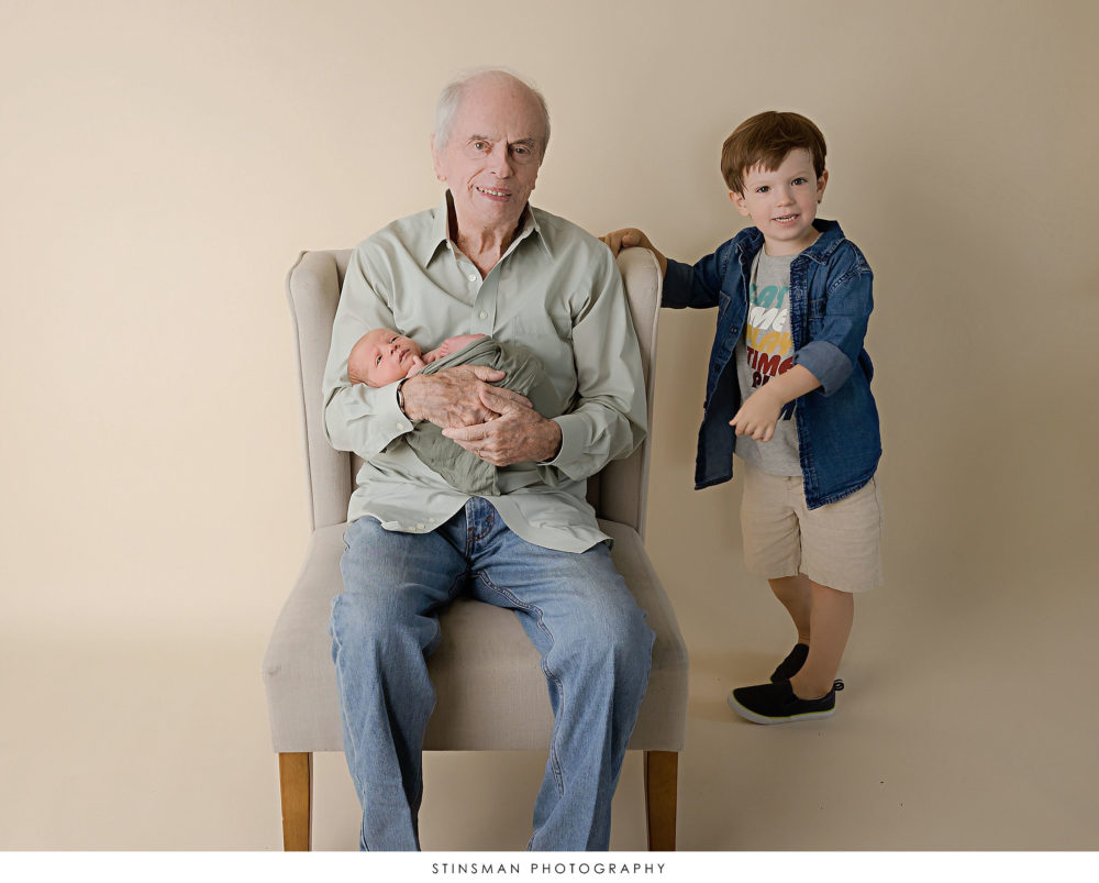Grandpa posing with his grandsons at a newborn photoshoot