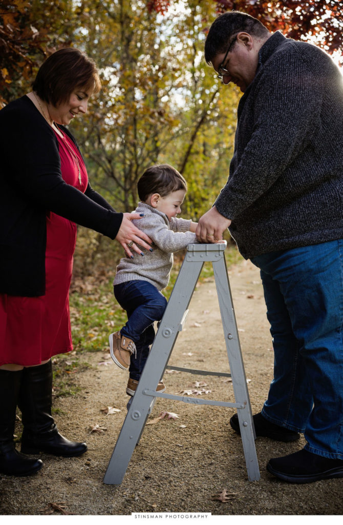 Little boy climbing a ladder with mom and dad at their family photoshoot