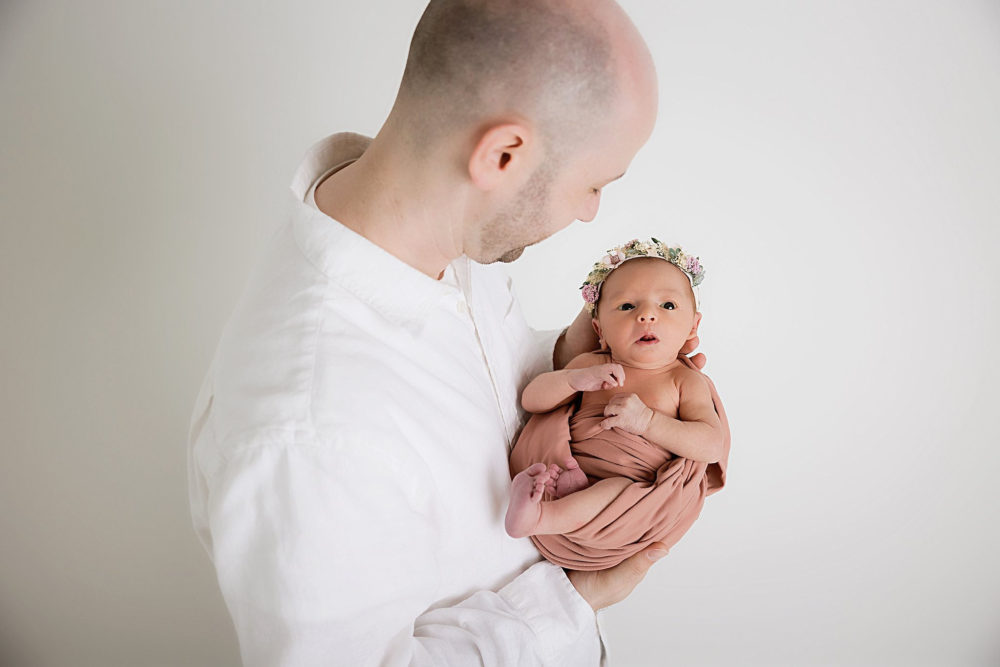 Newborn baby girl posed with her dad at her newborn photoshoot