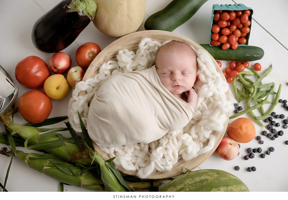 Newborn baby boy posed with vegetables at newborn photoshoot