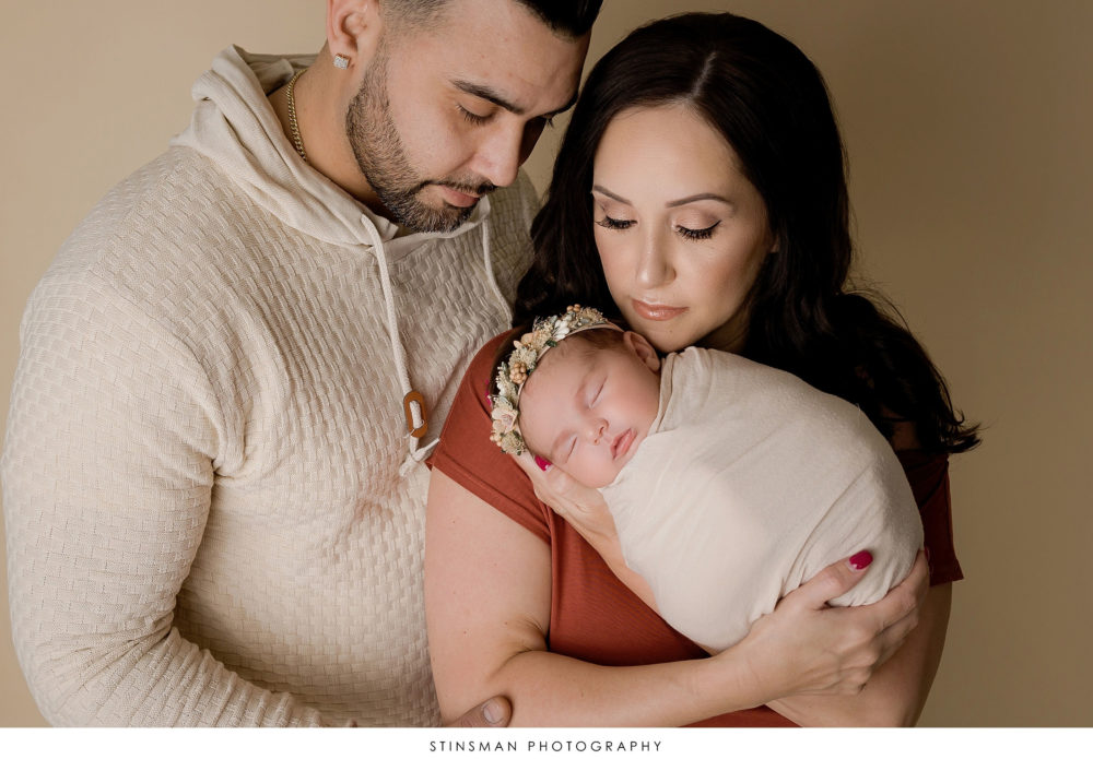 Mom and dad posing with their newborn baby girl at their newborn photoshoot