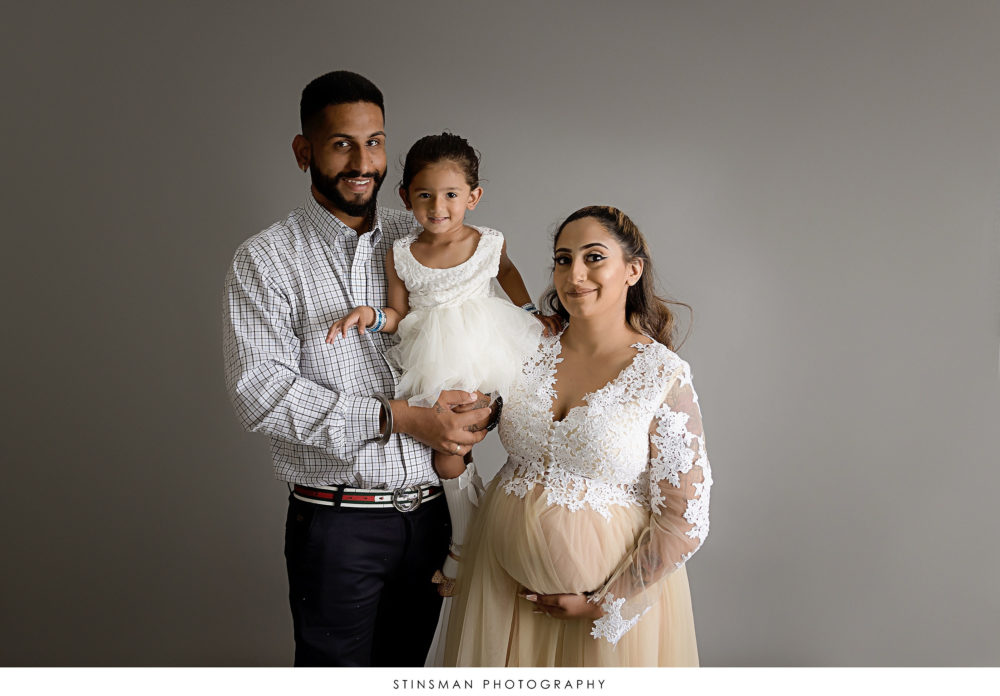 Pregnant mom, dad, and daughter posed at her maternity photoshoot