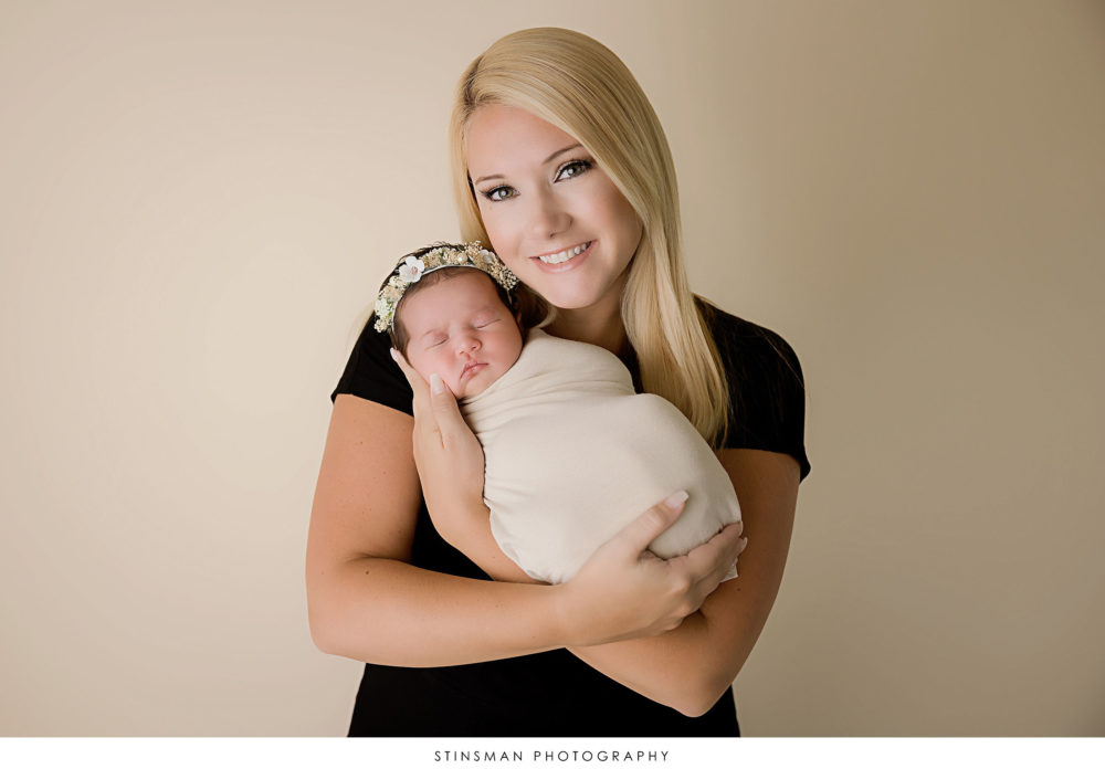 Newborn baby girl and her mom posed at her newborn photoshoot