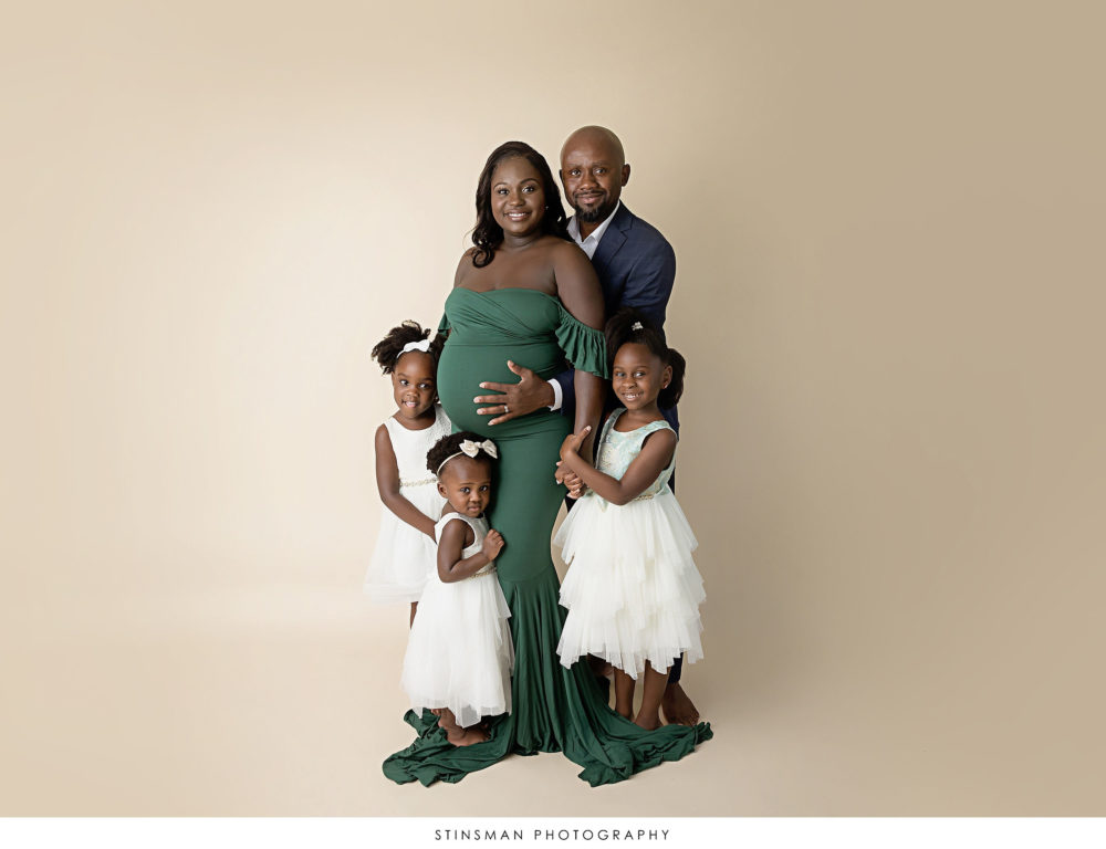 Expecting parents posing with their 3 girls at their maternity photoshoot
