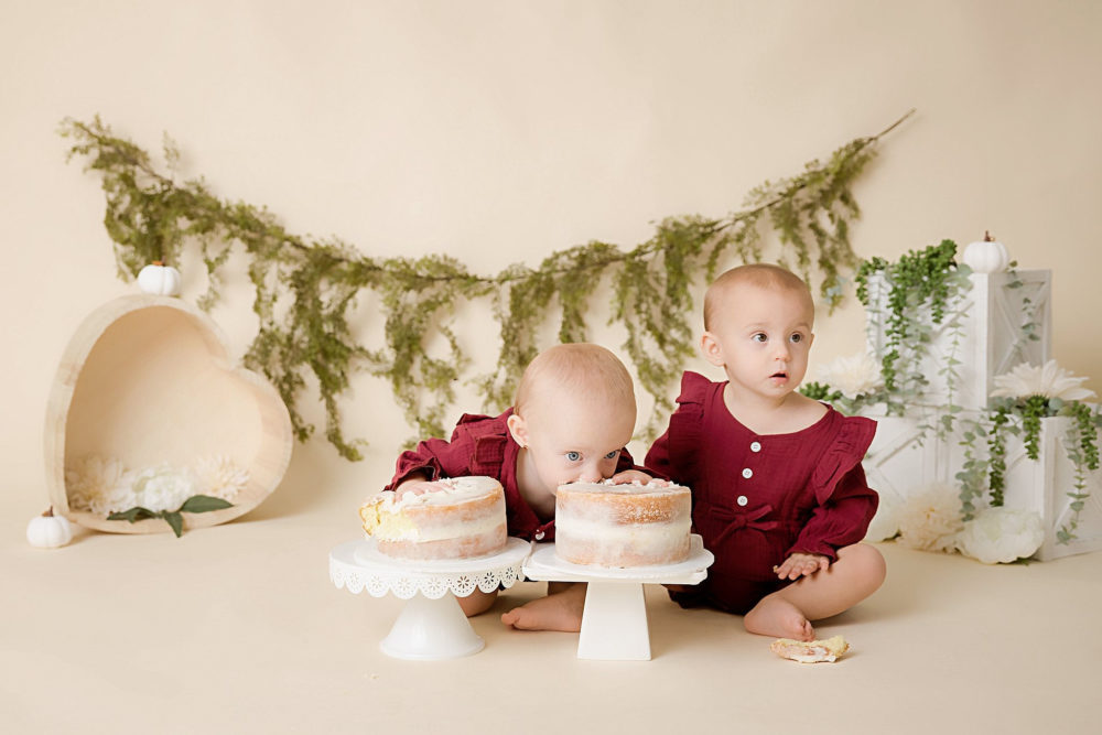 Twin girls posing with their cakes at milestone photoshoot