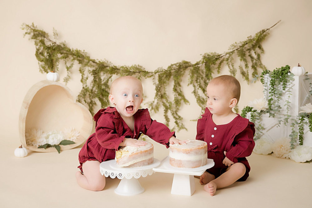 Twin girls posing with their cakes at their milestone photoshoo