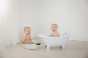 Twin girls in a bath at their milestone photoshoot