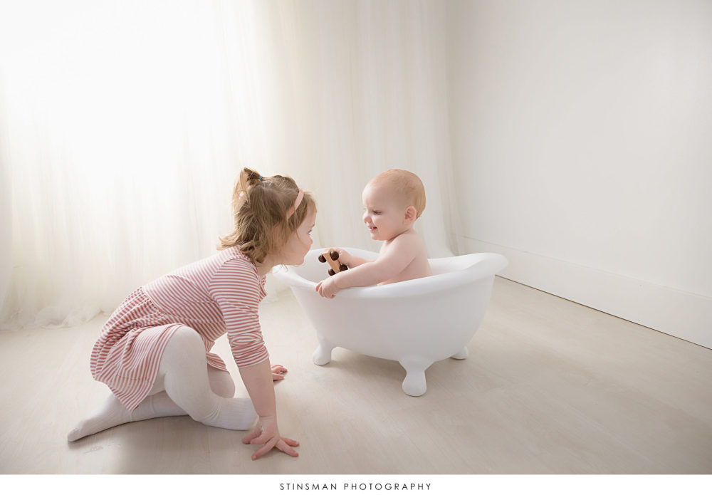 Baby boy playing with his sister at his milestone photoshoot