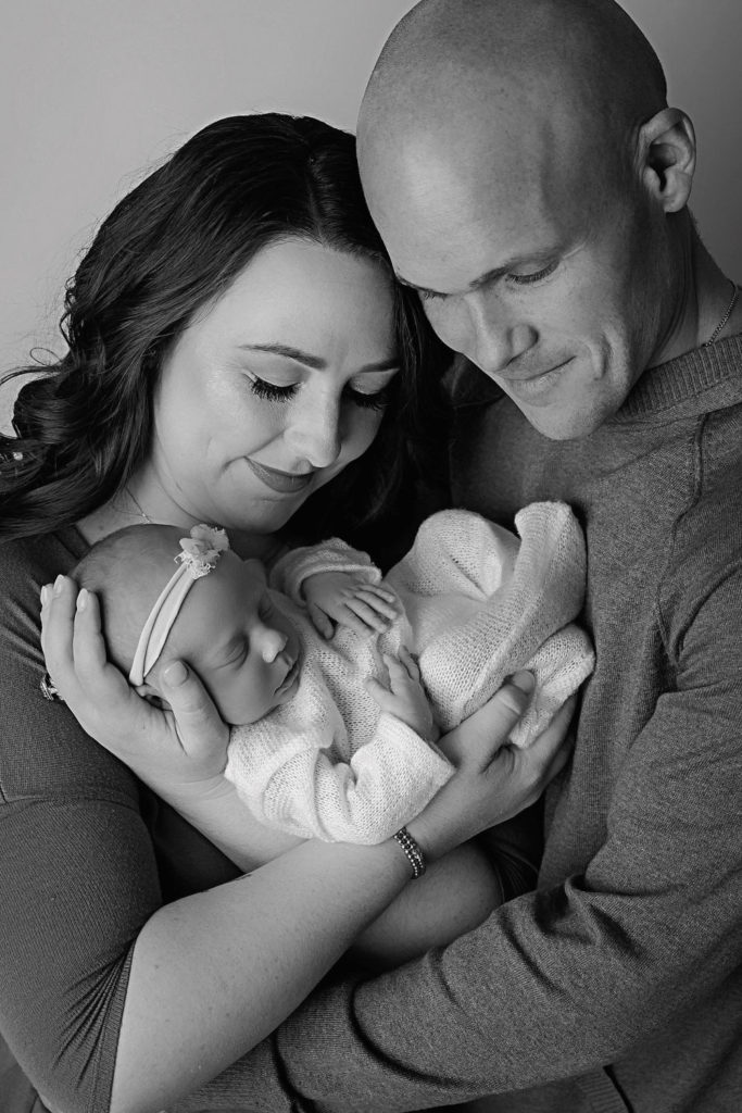 Mom and dad posing with their newborn baby girl at their newborn photoshoot